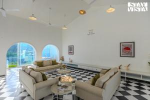 sala de estar con 2 sofás y suelo a cuadros en StayVista at Mudra Tattva - Pvt Pool,Lawn,Jacuzzi 2BR Luxury Rooms, en Suntikoppa