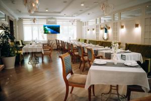 a restaurant with tables and chairs and a flat screen tv at Hotel Dastan Aktobe in Aktobe