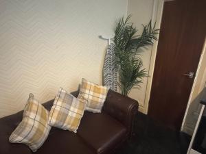 a brown leather couch with three pillows on it at Snug Studio - Minutes Walking from Pleasure Beach - Burlington Road in Blackpool