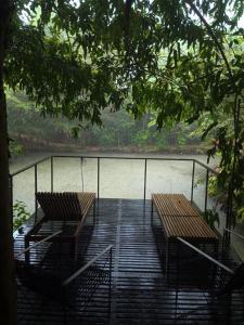 two benches sitting on a deck next to a body of water at Maligathenna in Nikawatawana