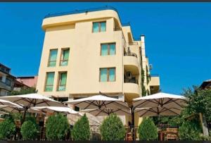 ein hohes Gebäude mit Sonnenschirmen davor in der Unterkunft Къща за гости Беглик таш 3 in Primorsko