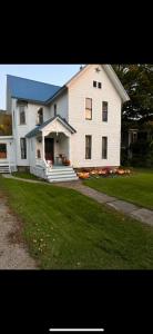 une maison blanche avec un toit bleu et une cour dans l'établissement Naples Wine Country 5BR Hot Tub Close to Bristol Mountain Skiing, à Naples