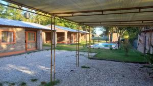 eine überdachte Terrasse mit einem Haus und einem Pool in der Unterkunft Cabañas en Oliveros in Oliveros