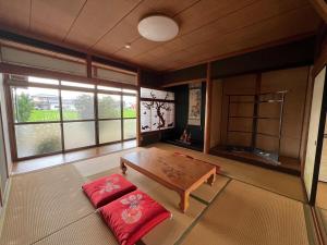 ein Wohnzimmer mit einem Holztisch und roten Kissen in der Unterkunft 瀬戸内庵Setouchian in Takamatsu