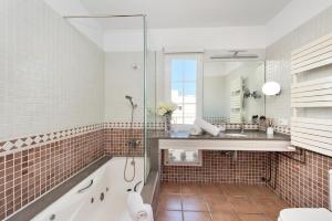 ein Badezimmer mit Badewanne, Waschbecken und Spiegel in der Unterkunft Casa con piscina y gran jardín in Colònia de Sant Pere + 26 Fotos