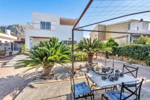eine Terrasse mit Palmen, einem Tisch und Stühlen in der Unterkunft Casa con piscina y gran jardín in Colònia de Sant Pere