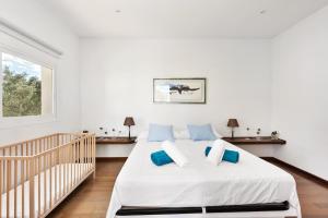 ein weißes Schlafzimmer mit einem Bett und einem Kinderbett in der Unterkunft Casa con piscina y gran jardín in Colònia de Sant Pere