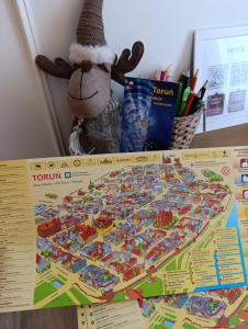 Um alce de brinquedo está sentado ao lado de um mapa de brinquedo. em Centrum Starówki Apartamenty Winnicy Gryf by Rentoom em Toruń