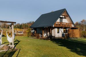 ein Haus mit einem schwarzen Dach auf einem Hof in der Unterkunft Domek nad Jeziorem Bogaczewo in Bogaczewo
