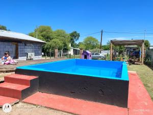 ein kleiner blauer Swimmingpool in einem Garten mit einem Mädchen in der Unterkunft Cabaña Anisacate in Villa Anizacate