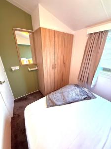 a bedroom with a bed and a wooden cabinet at The Eden - Camber Sands Cosy Spacious Caravan in Camber +42 photos