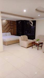 ein Schlafzimmer mit einem Bett, einer Couch und einem Tisch in der Unterkunft Ambassador Inn in Islamabad