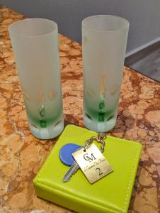 una mesa verde con dos vasos y un llavero en LE CAMERE DI VIA MECCIO, en Palermo