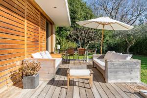 eine Holzterrasse mit einem Sofa und einem Sonnenschirm in der Unterkunft Provencal Villa Near Montpellier in Castelnau-le-Lez