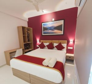 een slaapkamer met een groot bed met rode muren bij Elegant Residency in Coimbatore +17 foto's