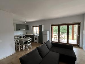 a living room with a black couch and a kitchen at Tra il bosco e il lago in Lorica
