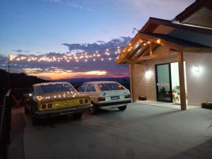 two cars parked next to a building with lights at Pousada Encantos de Itá in Itá