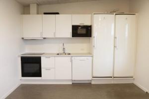 a kitchen with white cabinets and a refrigerator at Smart-Stay-Padborg in Padborg