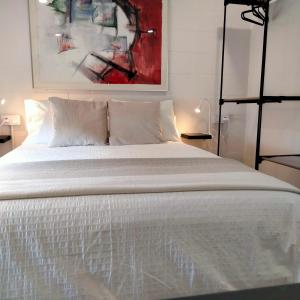 a bedroom with a white bed with a painting on the wall at Visitar La Campana in La Campana