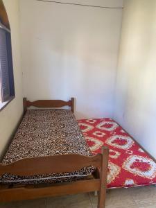 ein kleines Zimmer mit einem Bett mit einem roten Teppich in der Unterkunft Nataliana's House in Cabo Frio