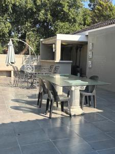 einen grünen Tisch und Stühle auf einer Terrasse in der Unterkunft Louvre Guesthouse in Bothaville + 18 Fotos