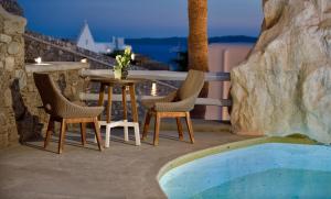 une table et des chaises assises sur une terrasse avec une piscine dans l'établissement Anax Resort and Spa, à Agios Ioannis Mykonos