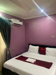 Un dormitorio con una cama con una pared morada. en MoAde, en Ikeja