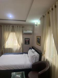 Un dormitorio con una cama, una silla y una ventana en MoAde, en Ikeja