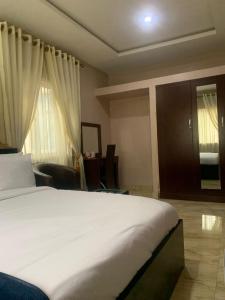 Un dormitorio con una gran cama blanca y ventanas. en MoAde, en Ikeja