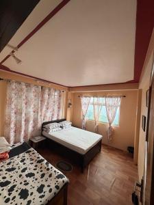 a bedroom with two beds and two windows at V V Homestay in Darjeeling