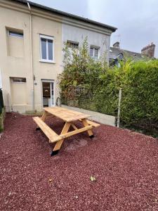 a wooden picnic table in front of a house at Maison Arques-la-Bataille à 5min de Dieppe in Arques-la-Bataille
