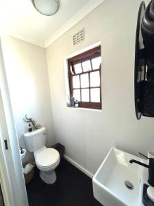 un bagno con un water, un lavandino e una finestra di De Kalkery Apartment a Kalk Bay Altre 6 foto
