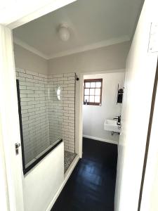 un bagno con doccia e lavandino di De Kalkery Apartment a Kalk Bay