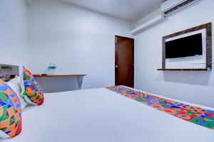 ein weißes Schlafzimmer mit Bett und Flachbildfernseher in der Unterkunft FabHotel World King in Pune