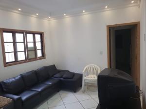 un salon avec un canapé noir et une télévision dans l'établissement Casa de praia, à Mongaguá