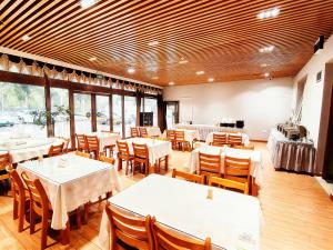 un restaurant avec des tables et des chaises blanches et des fenêtres dans l'établissement Greentree Inn Express Beijing Capital International Airport&格林豪泰智选酒店北京首都国际机场店, à Pékin