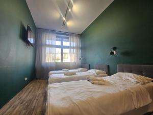 two beds in a room with green walls and a window at Place4You Studio w Sercu Ostródy in Ostróda +10 photos