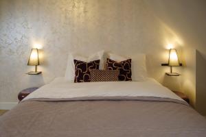 ein Schlafzimmer mit einem Bett mit Kissen und zwei Lampen in der Unterkunft De Parel - In de winkelstraat in Breda