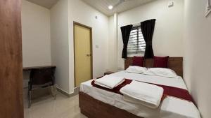 ein Schlafzimmer mit einem Bett mit roten und weißen Kissen in der Unterkunft Port Inn Lodge in Mangaluru