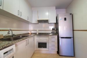 eine Küche mit weißen Schränken und einem Kühlschrank in der Unterkunft Global Properties, Piso practico, con terraza y piscina en la playa de Canet in Canet d'en Berenguer