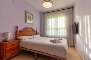 ein Schlafzimmer mit einem großen Bett und einem Fernseher in der Unterkunft Global Properties, Piso practico, con terraza y piscina en la playa de Canet in Canet d'en Berenguer + 21 Fotos