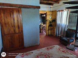 Cette chambre dispose d'une porte, d'une chaise et d'une table. dans l'établissement Cabaña Anisacate, à Villa Anizacate 1 autre photo