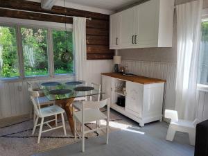 a kitchen with a glass table and white chairs at Villa Hattara - a cottage on the shore of a rapid in Nukari +46 photos