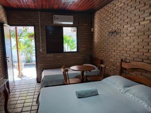 a room with two beds and a table and a window at Aluguel de suítes praia do frances in Marechal Deodoro +14 photos