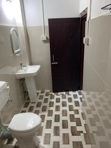a bathroom with a toilet and a sink and a black door at Prime Place Guesthouse in Dibrugarh