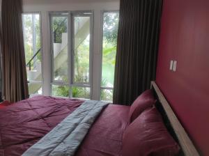 a bed in a bedroom with a large window at Embun Pagi Alami in Telukladang