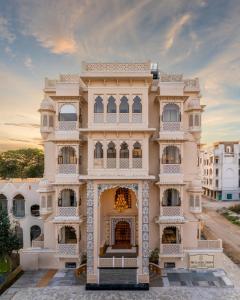 a large white building with a sunset in the background at The Classic Crown Udaipur - A Luxury Hotel by Lake Pichola in Jāmb