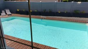 einen großen blauen Pool mit Holzterrasse in der Unterkunft Villa pour 24h auto le mans in Teloché