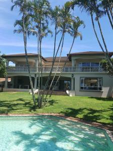 a house with palm trees and a swimming pool at Driftwood on 10 in Durban