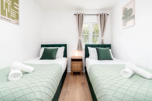 deux lits jumeaux dans une chambre avec fenêtre dans l'établissement Spacious 5 Bedroom 2 Bathroom Home with 12 Beds and Private Driveway Parking, à Manor